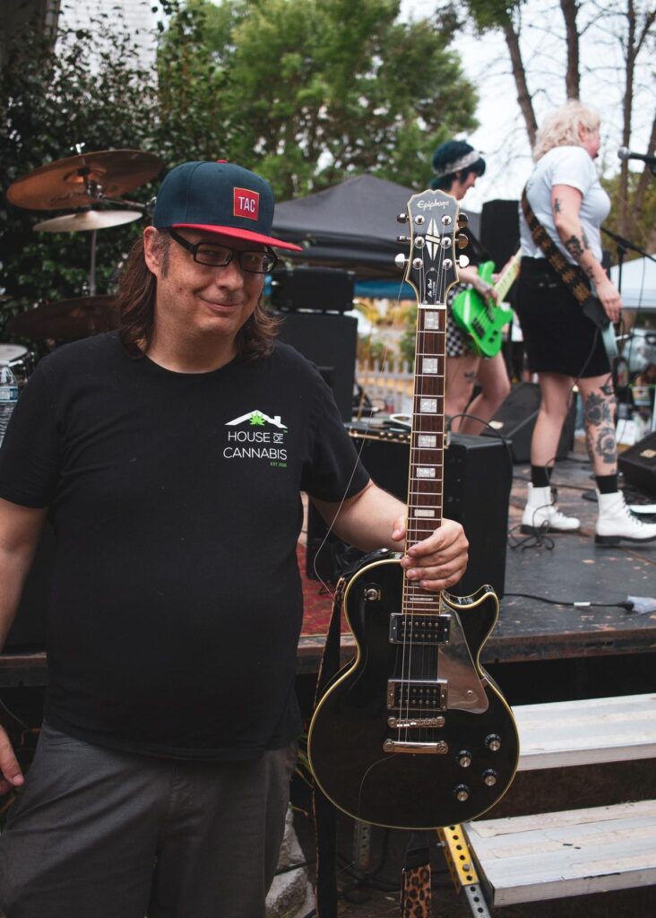 A picture of Kevin, holding the fabled guitar with the broken string at Tacoma Porchfest